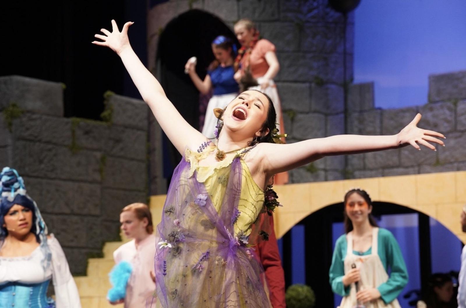 Clara Neag on stage, arms outstretched mid-number
